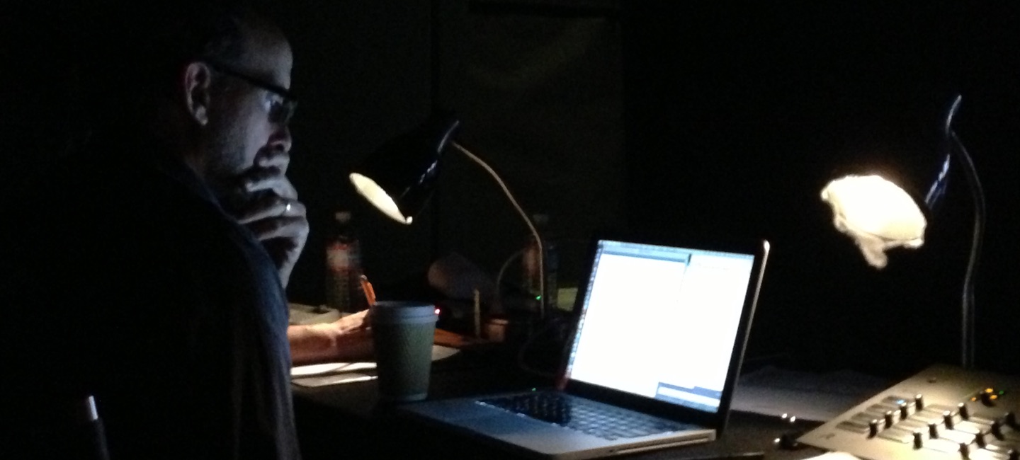 Jay Martel reviewing a script on his laptop in a darkened writers' room
